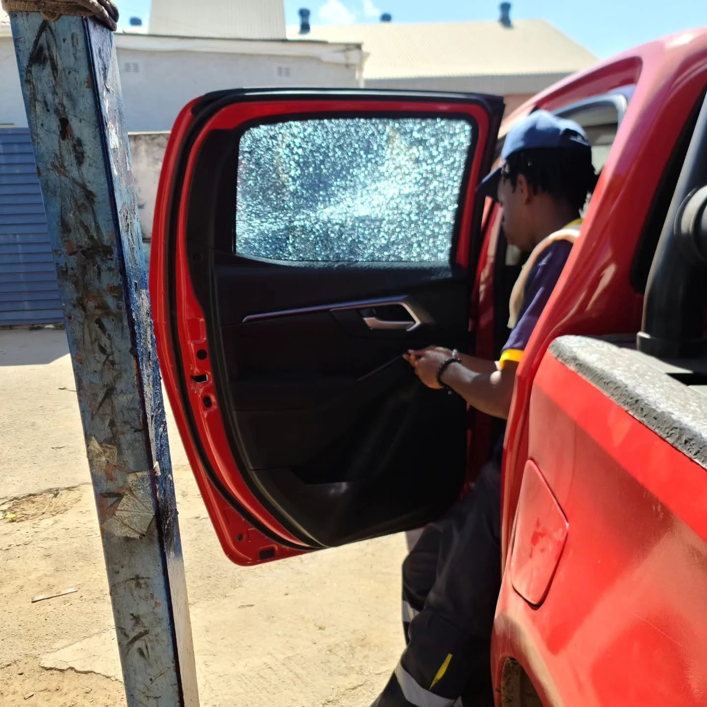 Protective film holding shattered glass in a red vehicle door